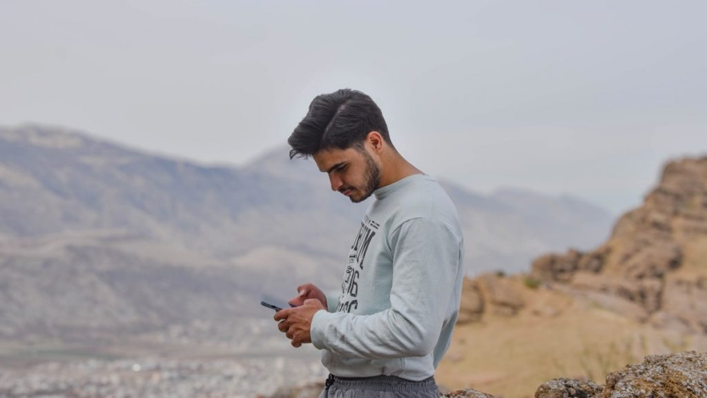 a man sitting on a rock looking at his cell phone