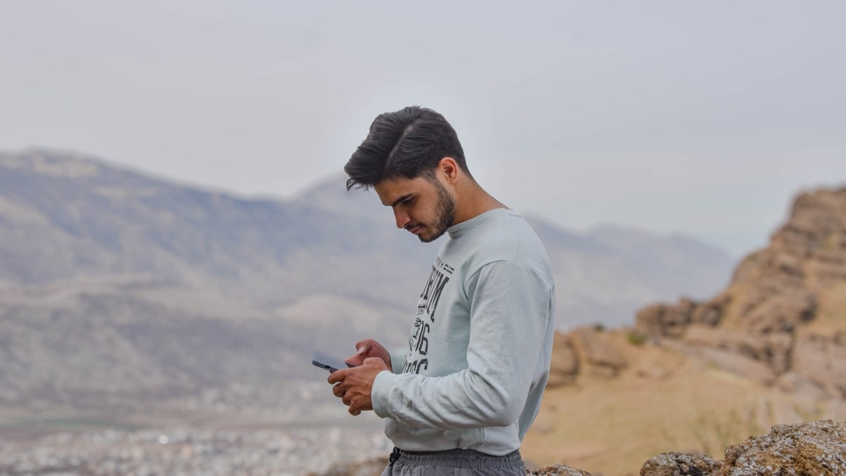 a man sitting on a rock looking at his cell phone